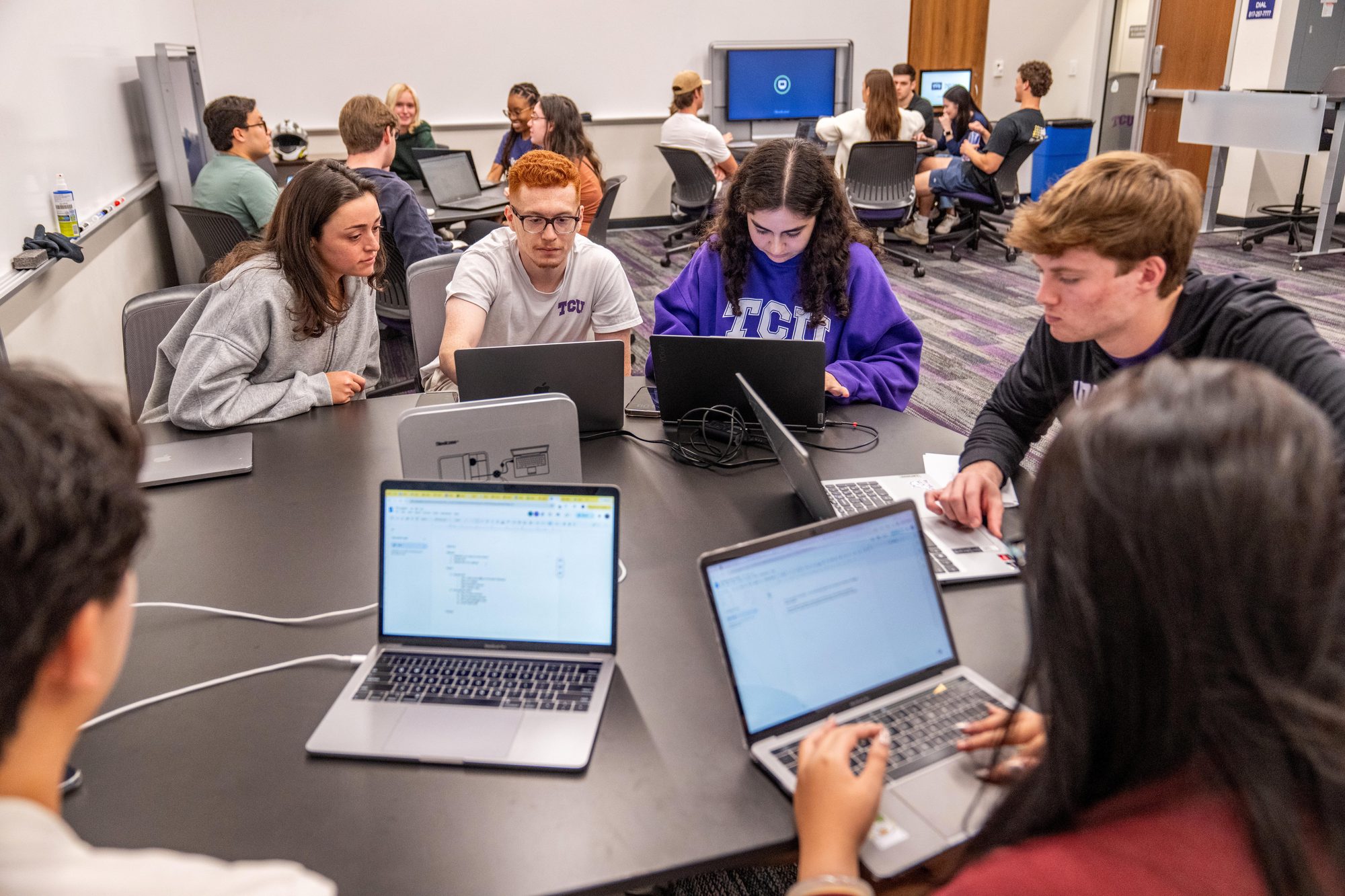 TCU students working together on laptops in a Neeley classroom